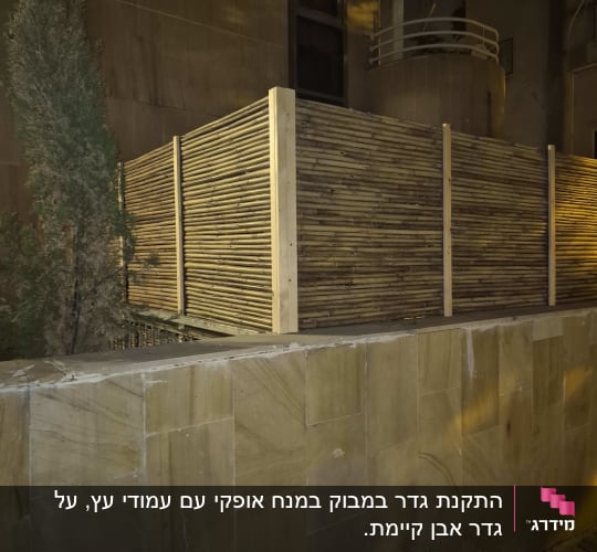 גדר עץ במבוק ליד קיר אבן